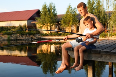 Dad and son fishing together on sunny day