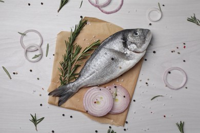 Photo of Raw dorado fish, spices and onion on white wooden table, flat lay