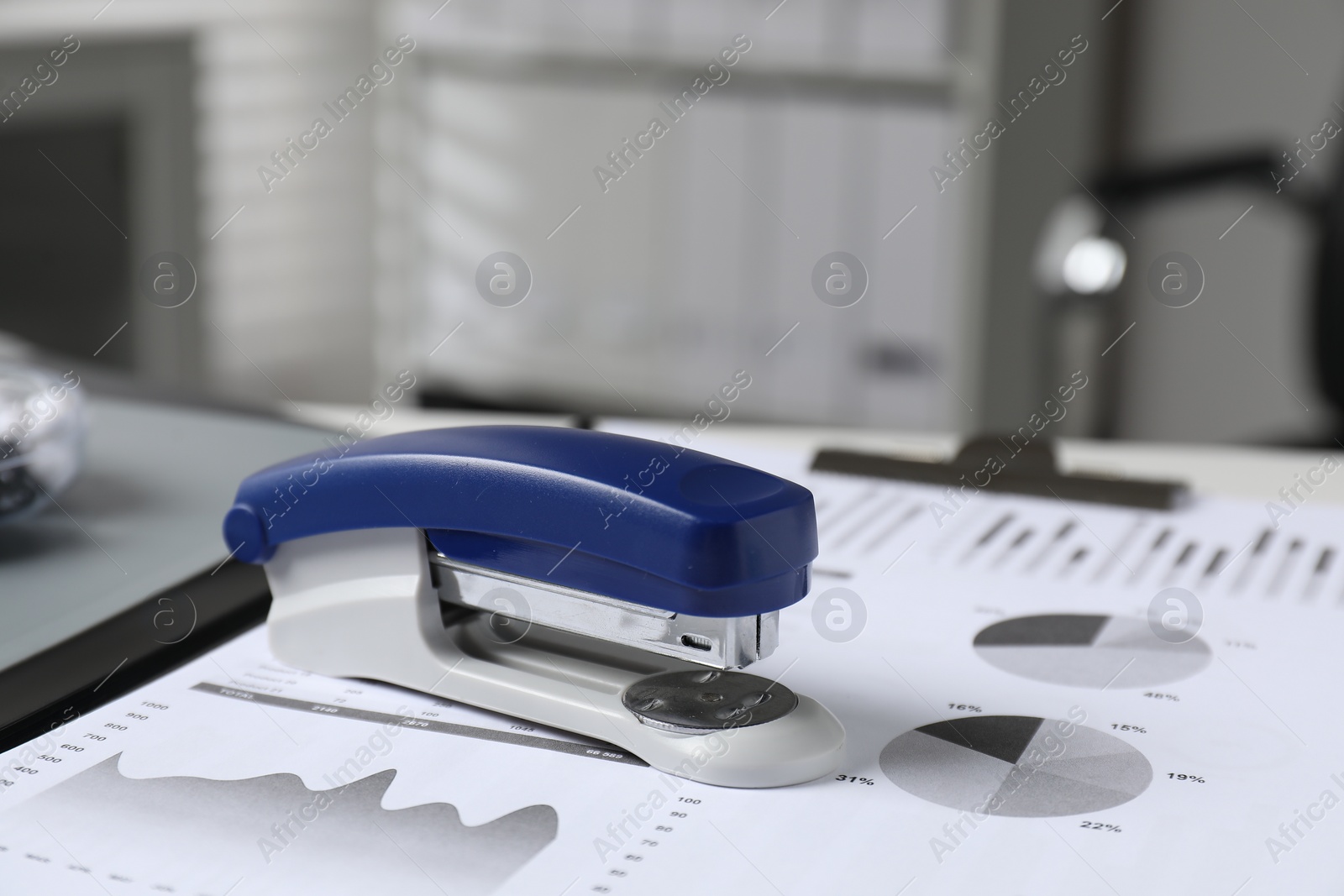 Photo of Stapler and document on table indoors, closeup