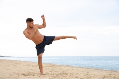 Photo of Muscular man doing exercise on beach. Body training
