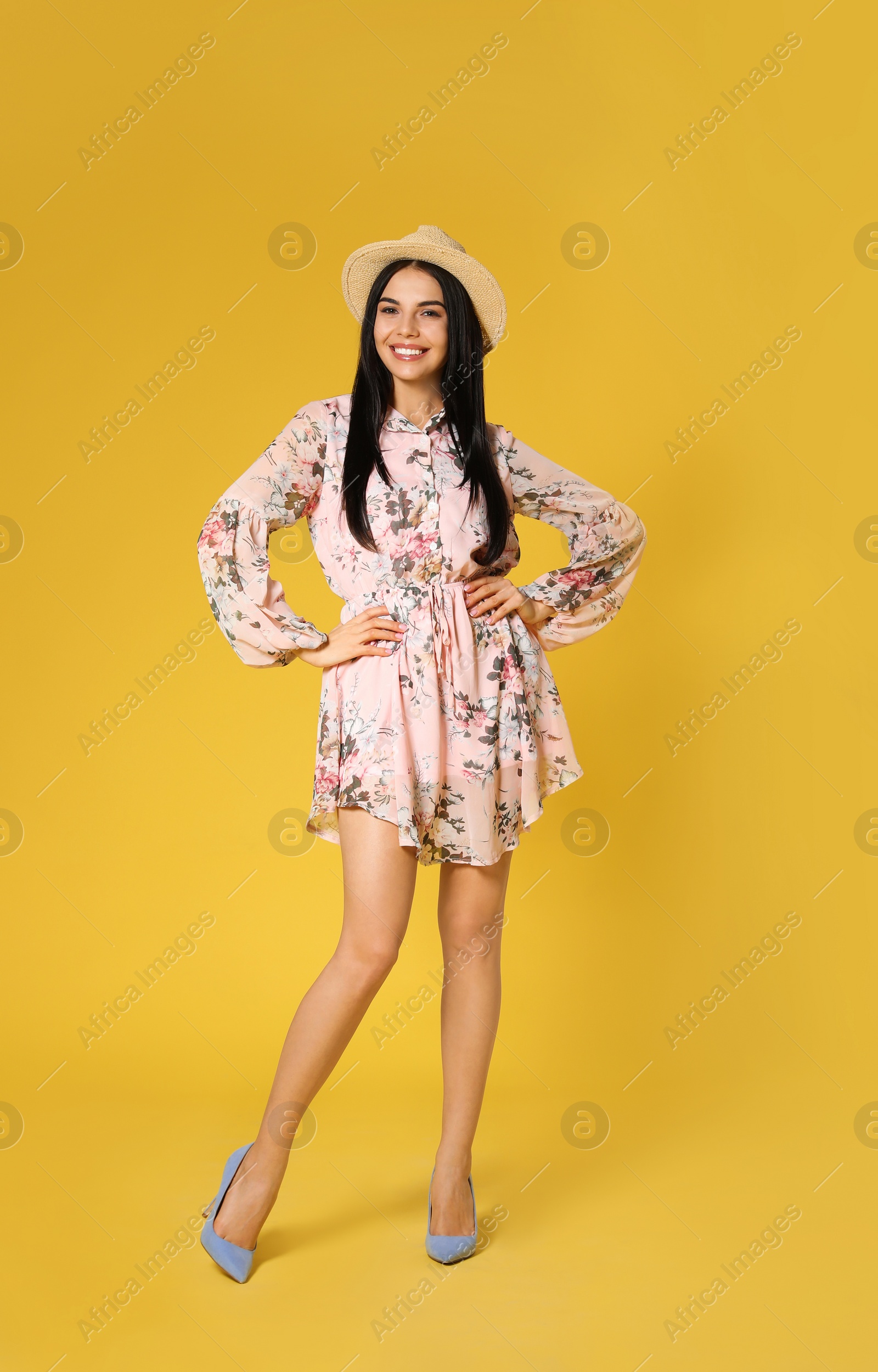 Photo of Young woman wearing floral print dress and straw hat on yellow background