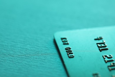 Photo of One credit card on turquoise background, closeup. Space for text