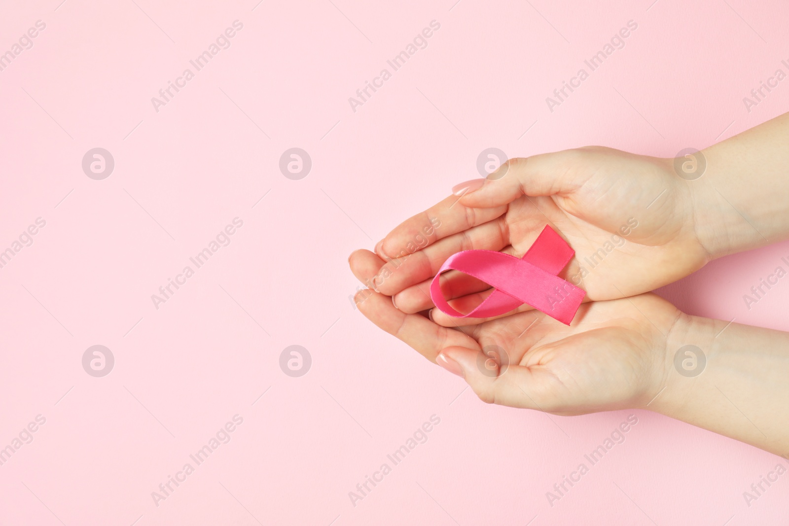 Photo of Breast cancer awareness. Woman with pink ribbon on color background, top view. Space for text