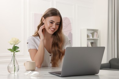 Photo of Happy woman with laptop at white table