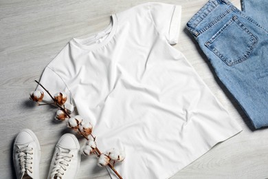 Stylish t-shirt, sneakers and jeans on white wooden background, flat lay