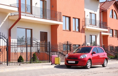 Photo of Color suitcases near family car in city. Space for text