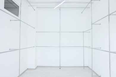 Photo of Empty room with beautiful white walls and garment racks during repair