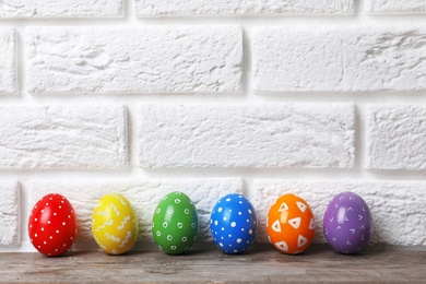 Photo of Decorated Easter eggs on table near brick wall. Space for text