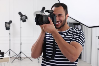 Young professional photographer taking picture in modern photo studio, space for text