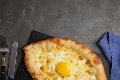 Photo of Fresh homemade khachapuri with cheese and egg served on grey table, flat lay. Space for text