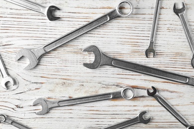 New wrenches on wooden background, top view. Plumber tools