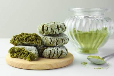 Photo of Board with stacked tasty matcha cookies and powder on white table, closeup