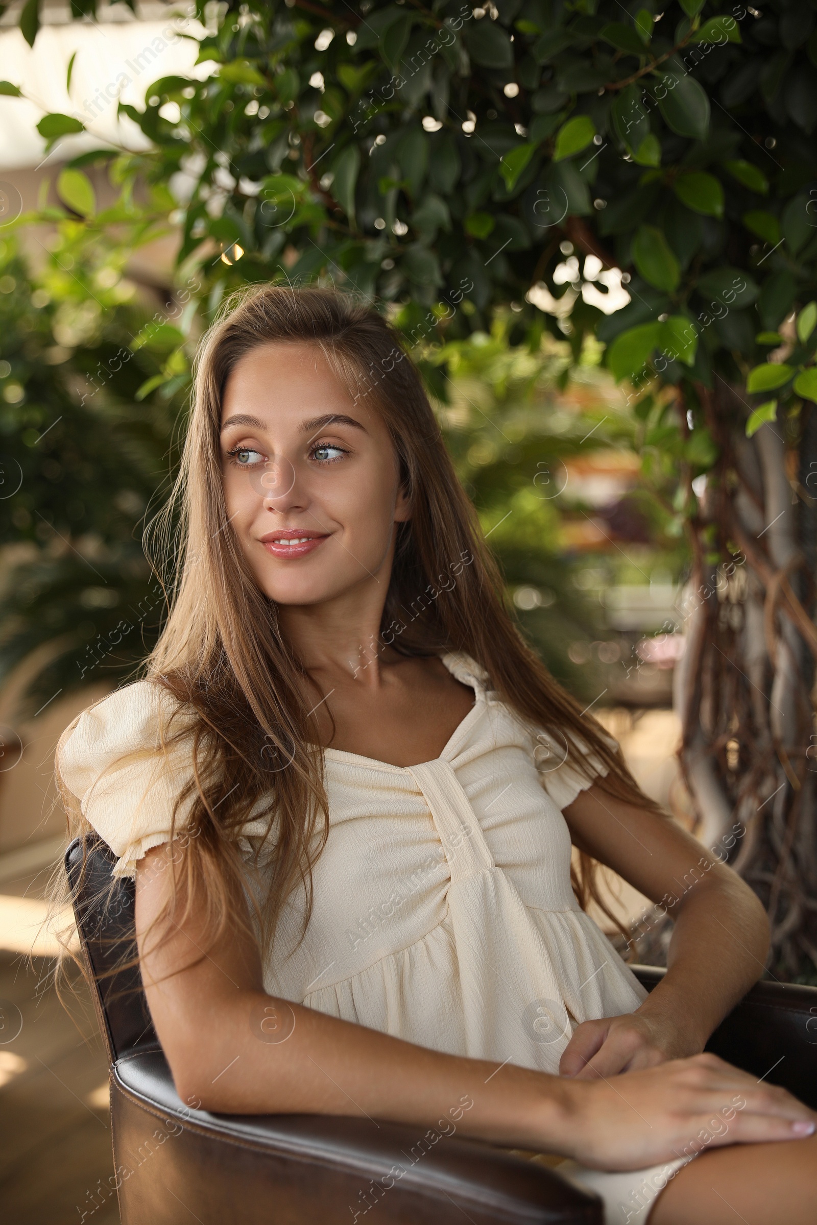 Photo of Beautiful young woman sitting on indoor terrace in cafe