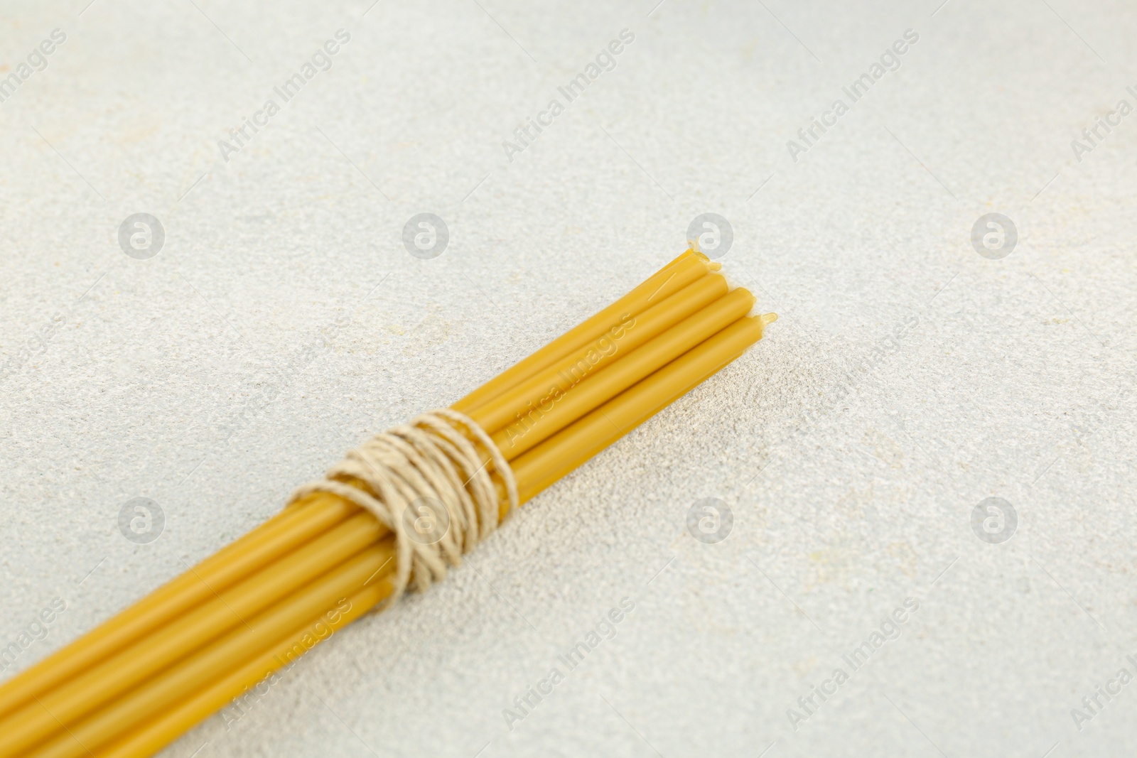 Photo of Bunch of church candles on white textured table, closeup. Space for text