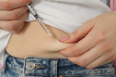 Photo of Diabetes. Woman making insulin injection into her belly, closeup