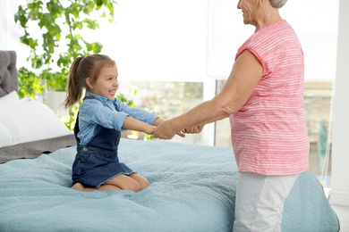 Photo of Cute girl and her grandmother playing together at home