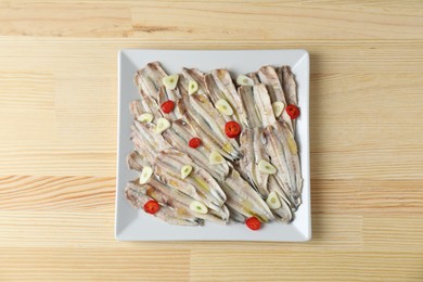 Photo of Tasty pickled anchovies with garlic and chili pepper on wooden table, top view