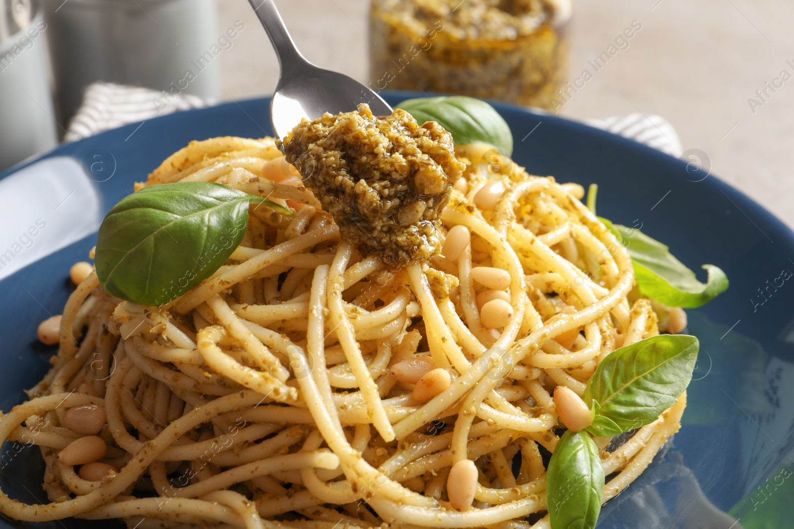Photo of Dressing delicious pasta with basil pesto sauce, closeup