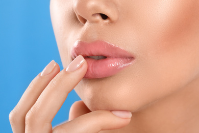 Photo of Young woman with beautiful full lips on light blue background, closeup