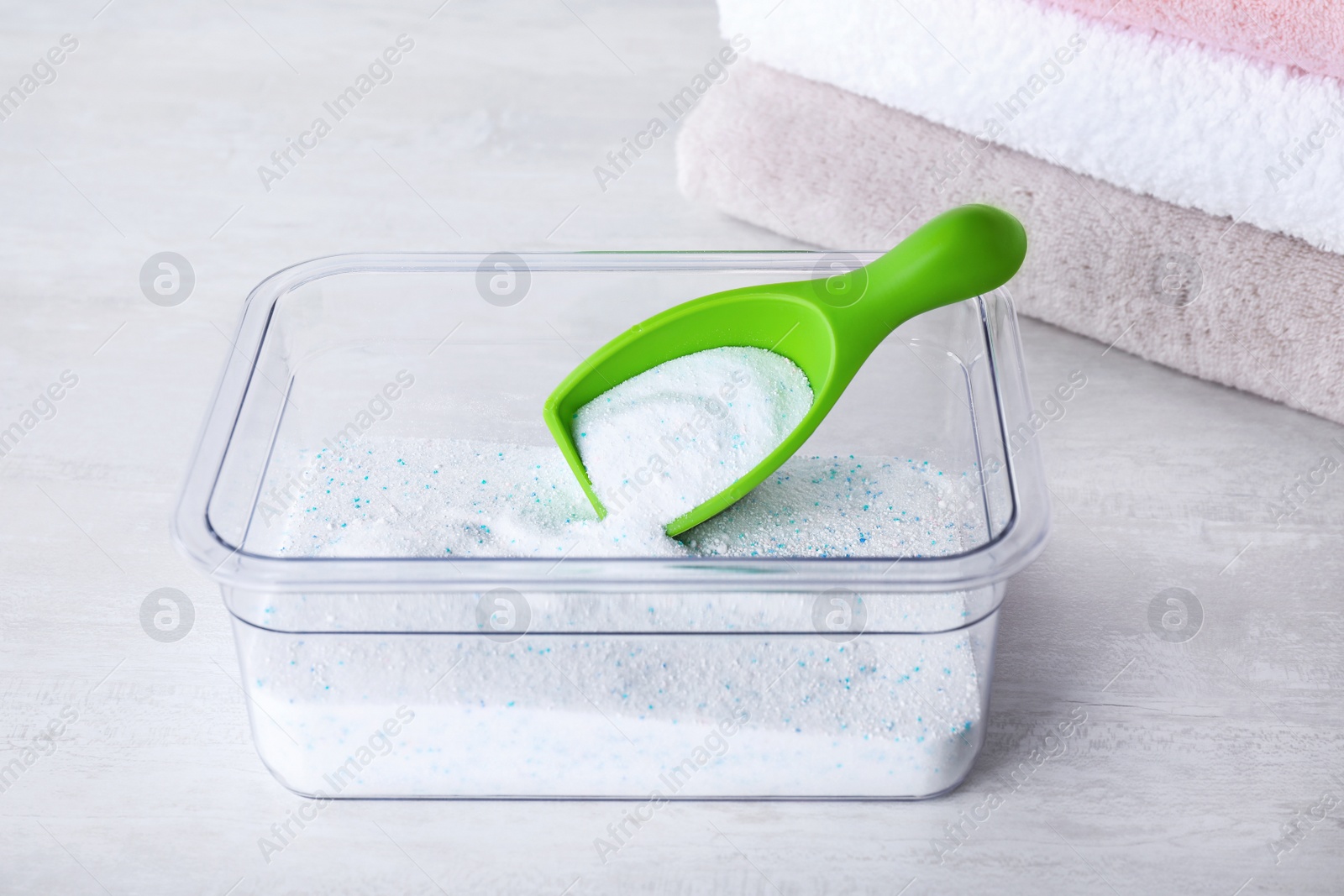 Photo of Container and measuring scoop with laundry powder on white table