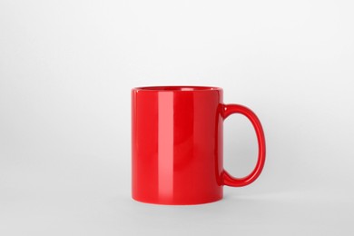 Photo of Blank red ceramic mug on light background