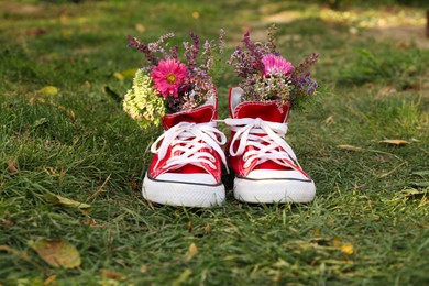 Photo of Shoes with beautiful flowers on grass outdoors