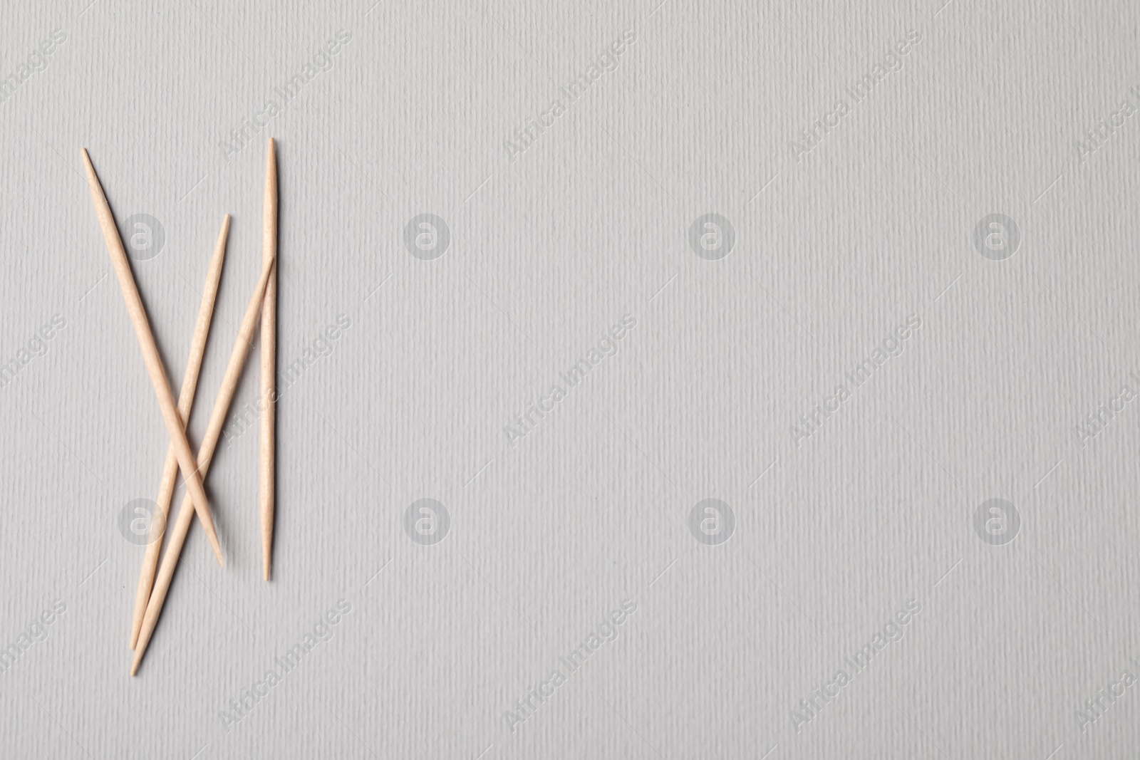 Photo of Wooden toothpicks on grey background, flat lay. Space for text