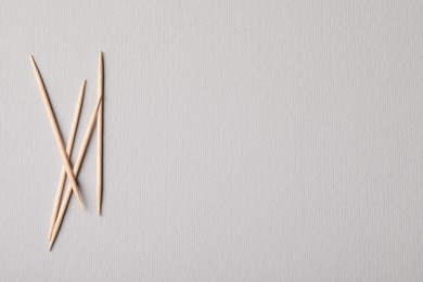 Wooden toothpicks on grey background, flat lay. Space for text