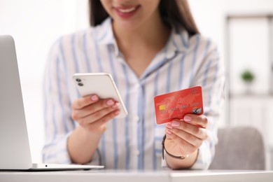 Photo of Woman with credit card using smartphone for online shopping at white table, closeup