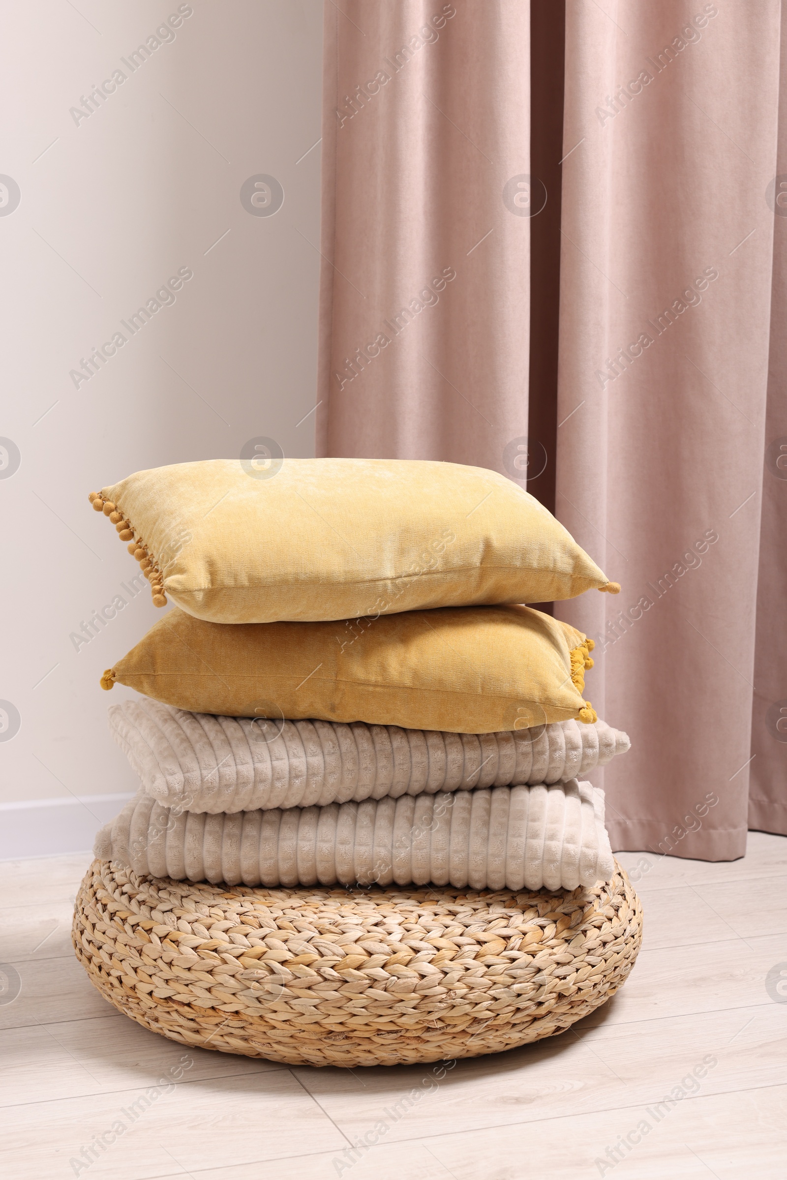 Photo of Soft pillows on wicker pouf in room