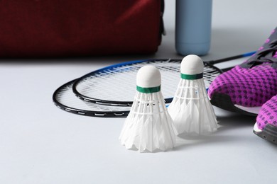 Feather badminton shuttlecocks, rackets and sneakers on gray background