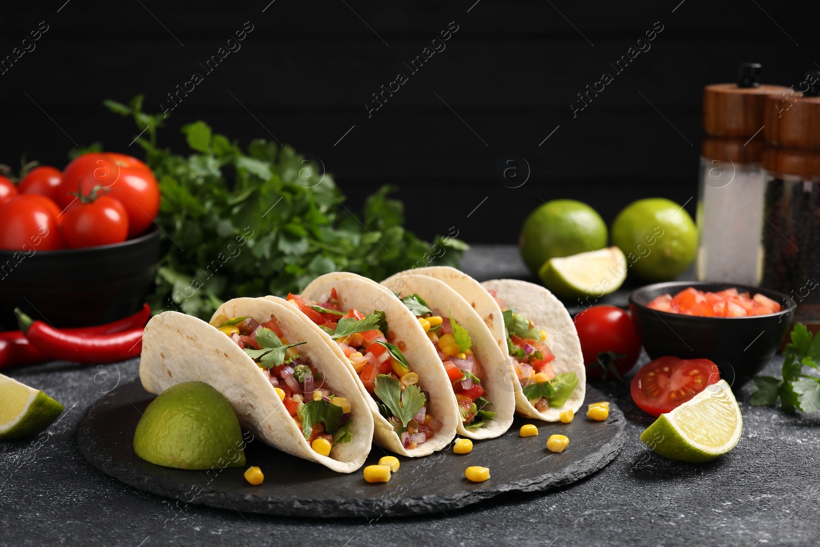 Photo of Tasty tacos with vegetables on black textured table