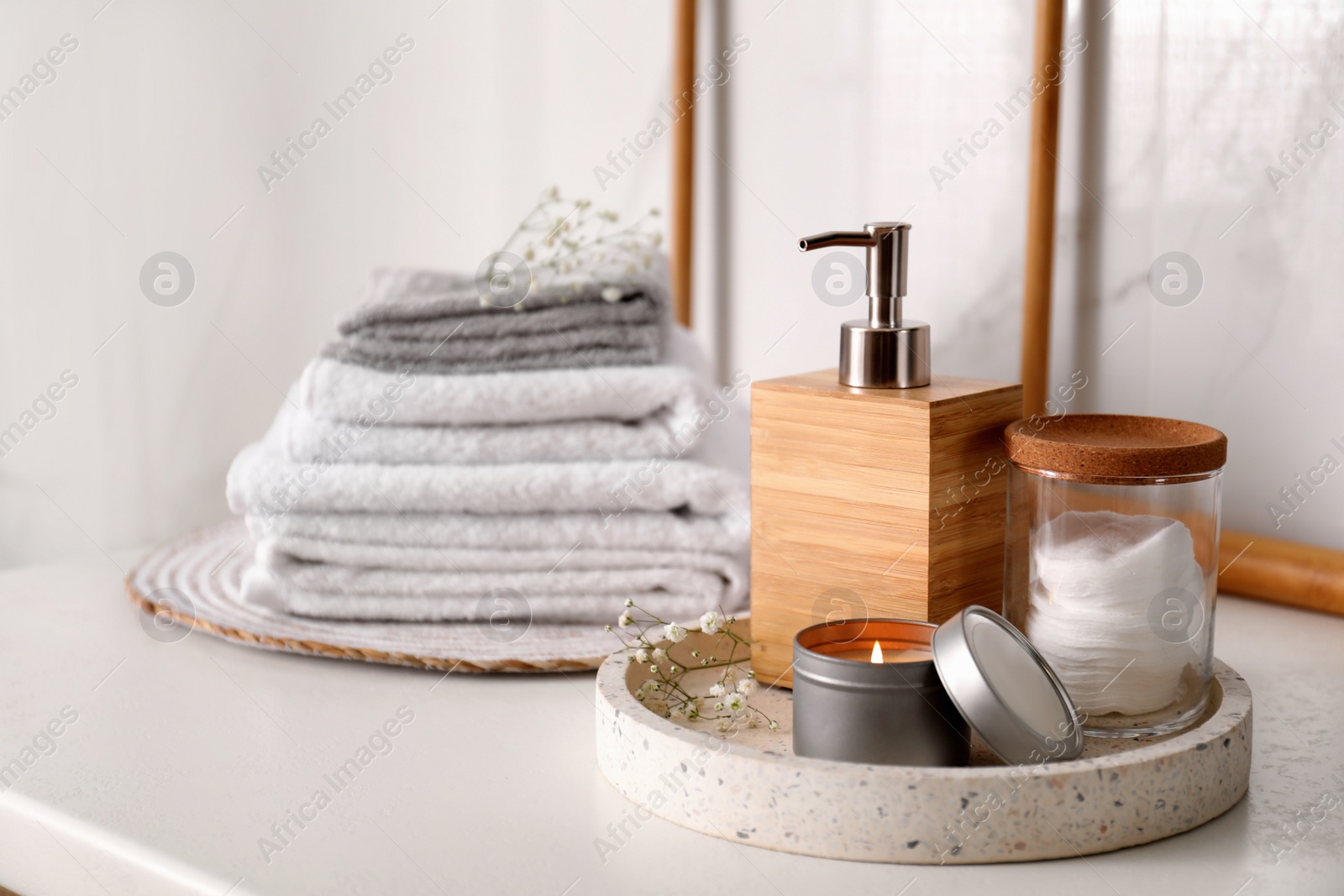 Photo of Tray with soap dispenser, cotton pads and burning candle on countertop in bathroom. Space for text