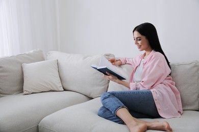 Woman reading book on sofa in living room