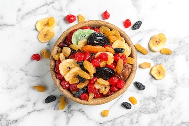 Photo of Bowl with different dried fruits on marble background, top view. Healthy lifestyle