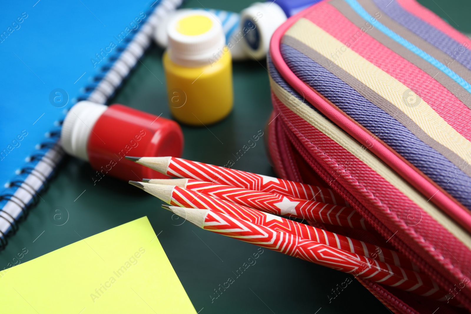 Photo of Different colorful stationery on chalkboard surface. Back to school