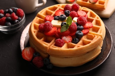 Tasty Belgian waffles with fresh berries and cheese on black table, closeup