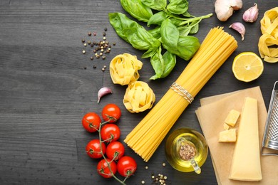 Photo of Different types of pasta, products and peppercorns on dark wooden table, flat lay. Space for text