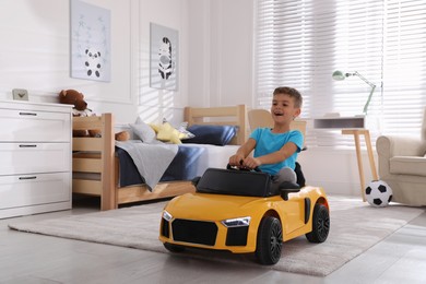 Photo of Cute little boy driving big toy car at home