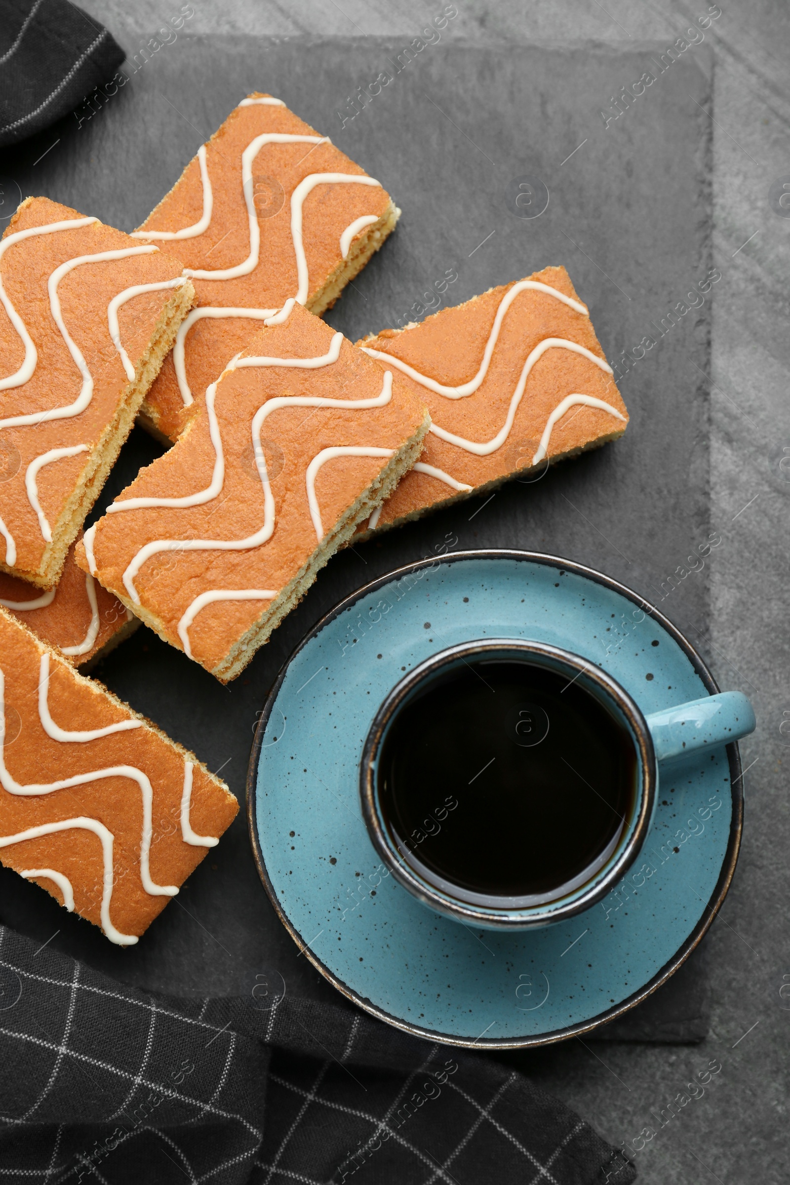 Photo of Tasty sponge cakes and hot drink on grey table, flat lay