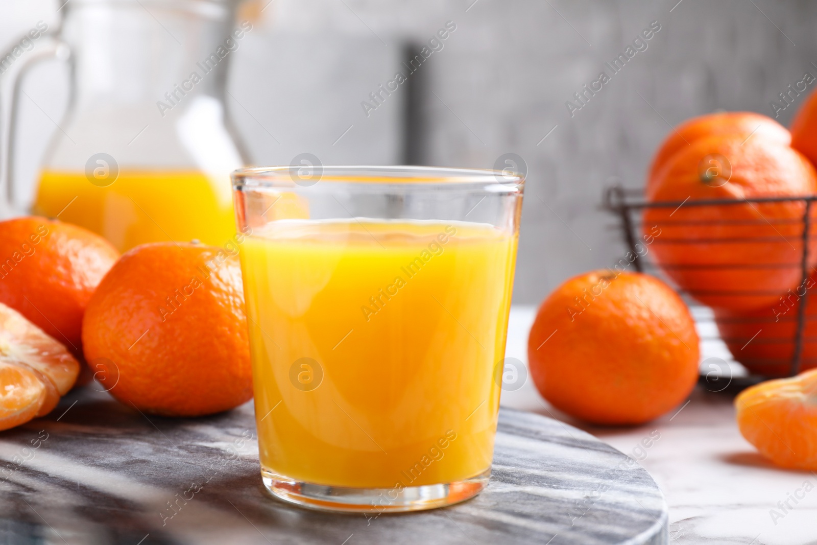 Photo of Glass of fresh tangerine juice and fruits on board