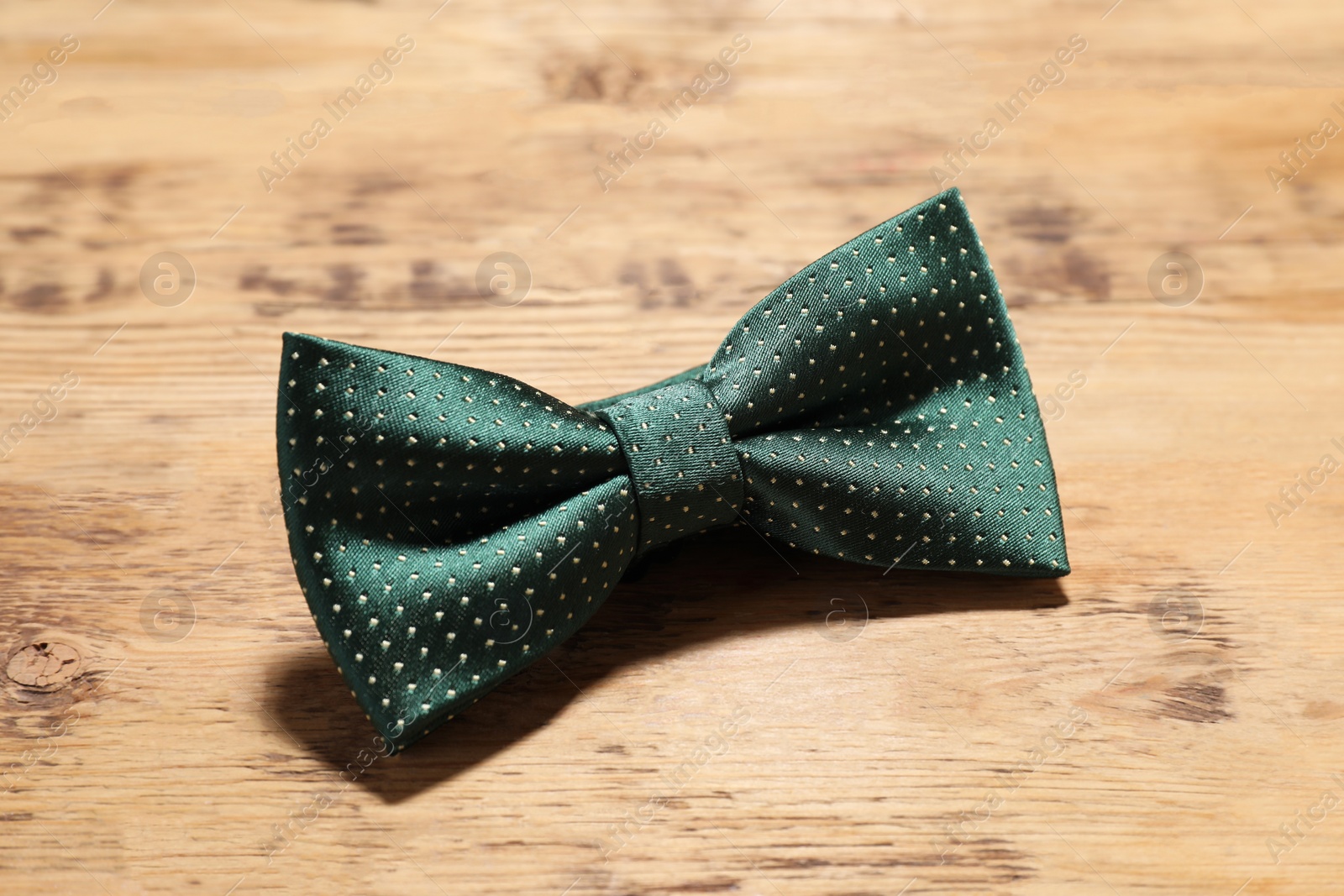 Photo of Stylish green bow tie with polka dot pattern on wooden table