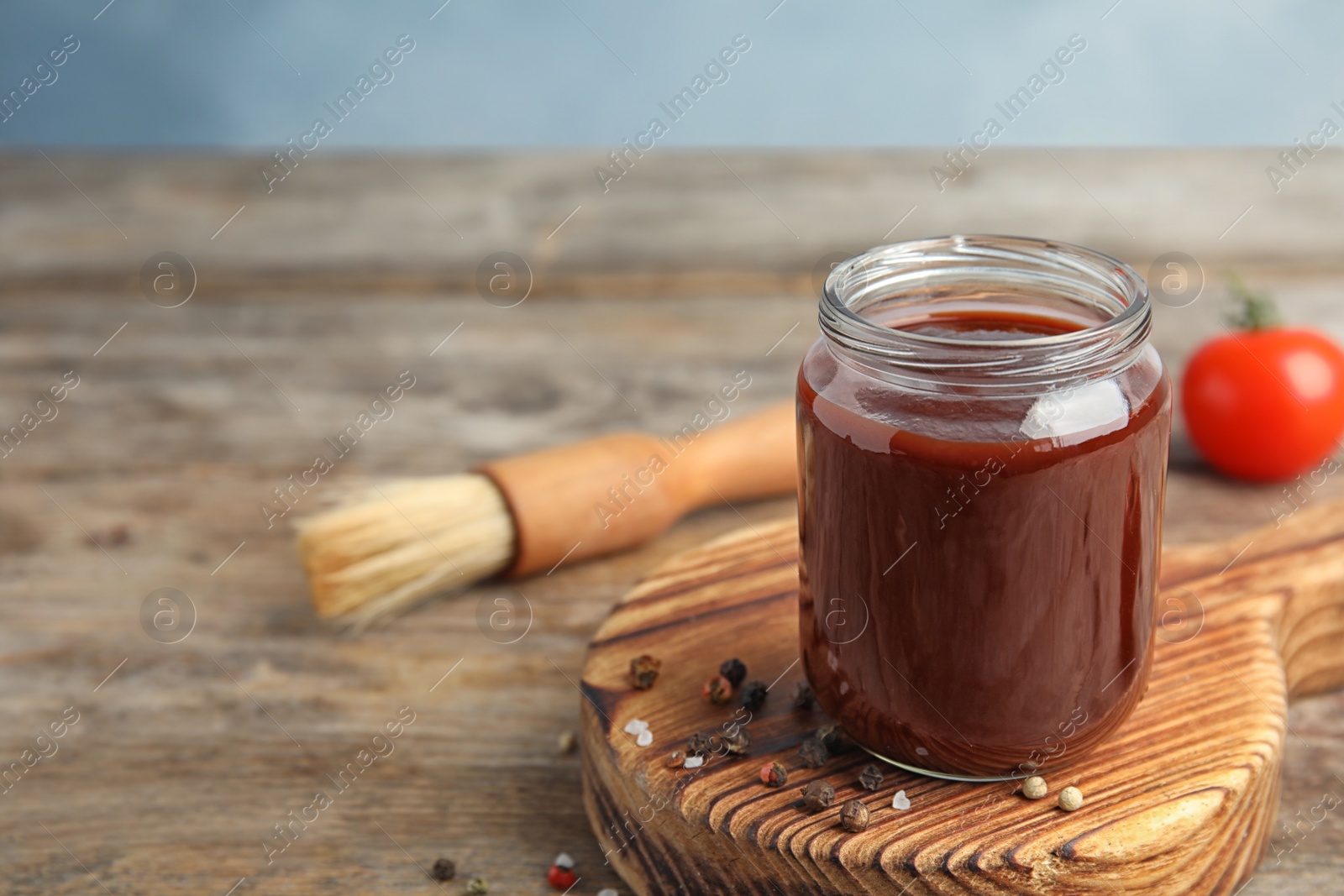 Photo of Composition with jar of barbecue sauce on wooden table. Space for text