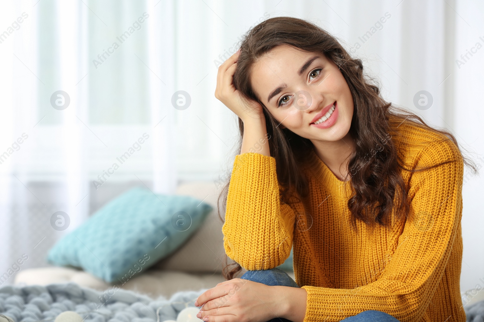 Photo of Portrait of young beautiful woman in warm sweater on bed at home