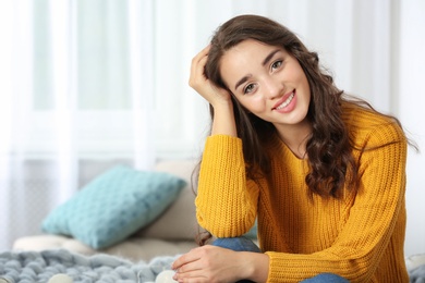 Photo of Portrait of young beautiful woman in warm sweater on bed at home