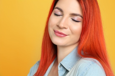 Photo of Young woman with bright dyed hair on yellow background, closeup