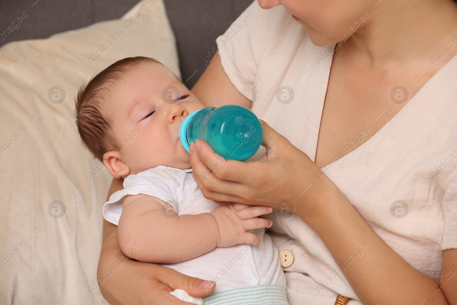 Photo of Mother feeding her cute child with infant formula indoors