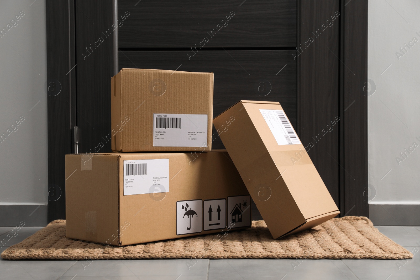 Photo of Cardboard boxes on floor mat near entrance. Parcel delivery service