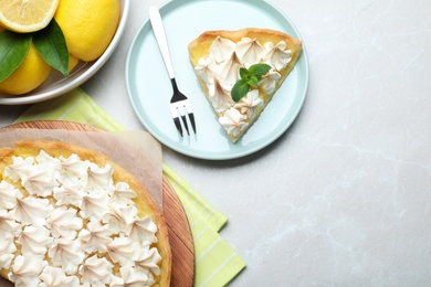 Photo of Cut delicious lemon meringue pie served on light table, flat lay. Space for text