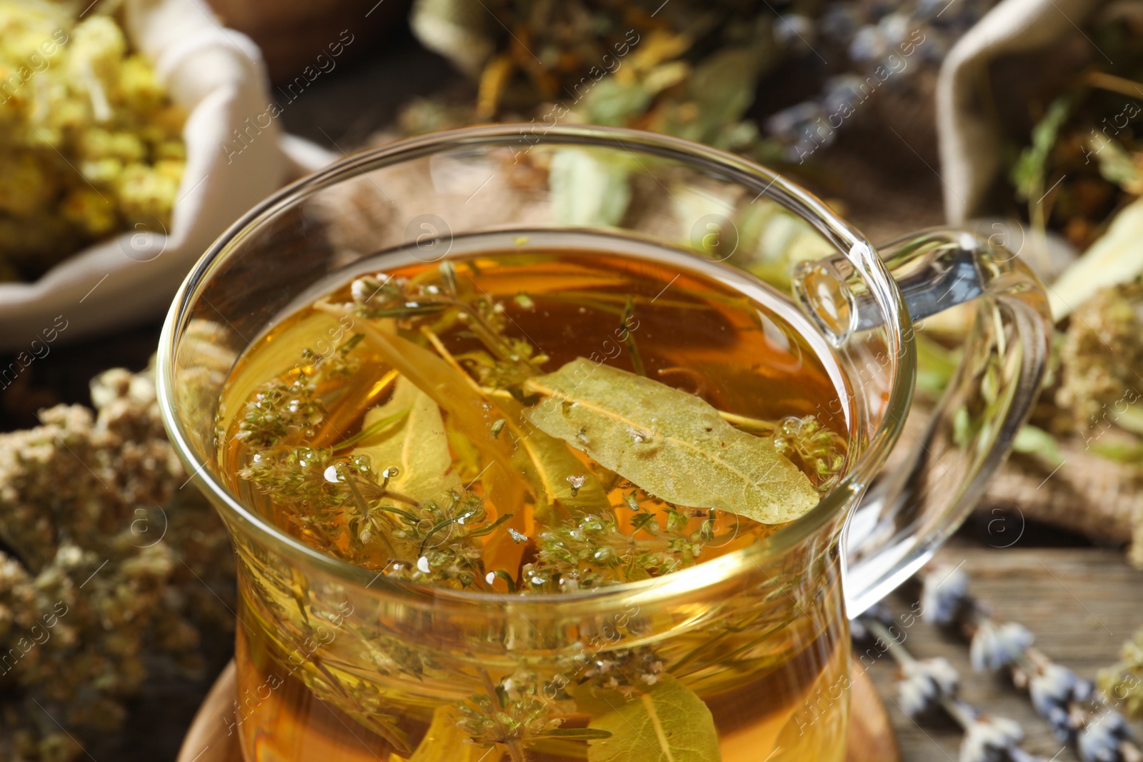 Photo of Freshly brewed tea and dried herbs on table, closeup